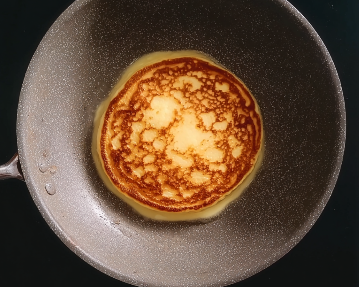 Golden pancake cooking in pan