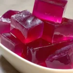 Gelée rose en cubes brillants dans un plat blanc