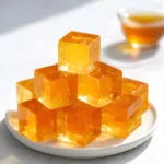 Golden gelatin cubes stacked on white plate