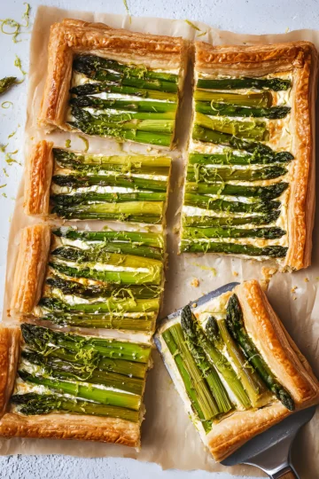 asparagus tart sliced on parchment with spatula