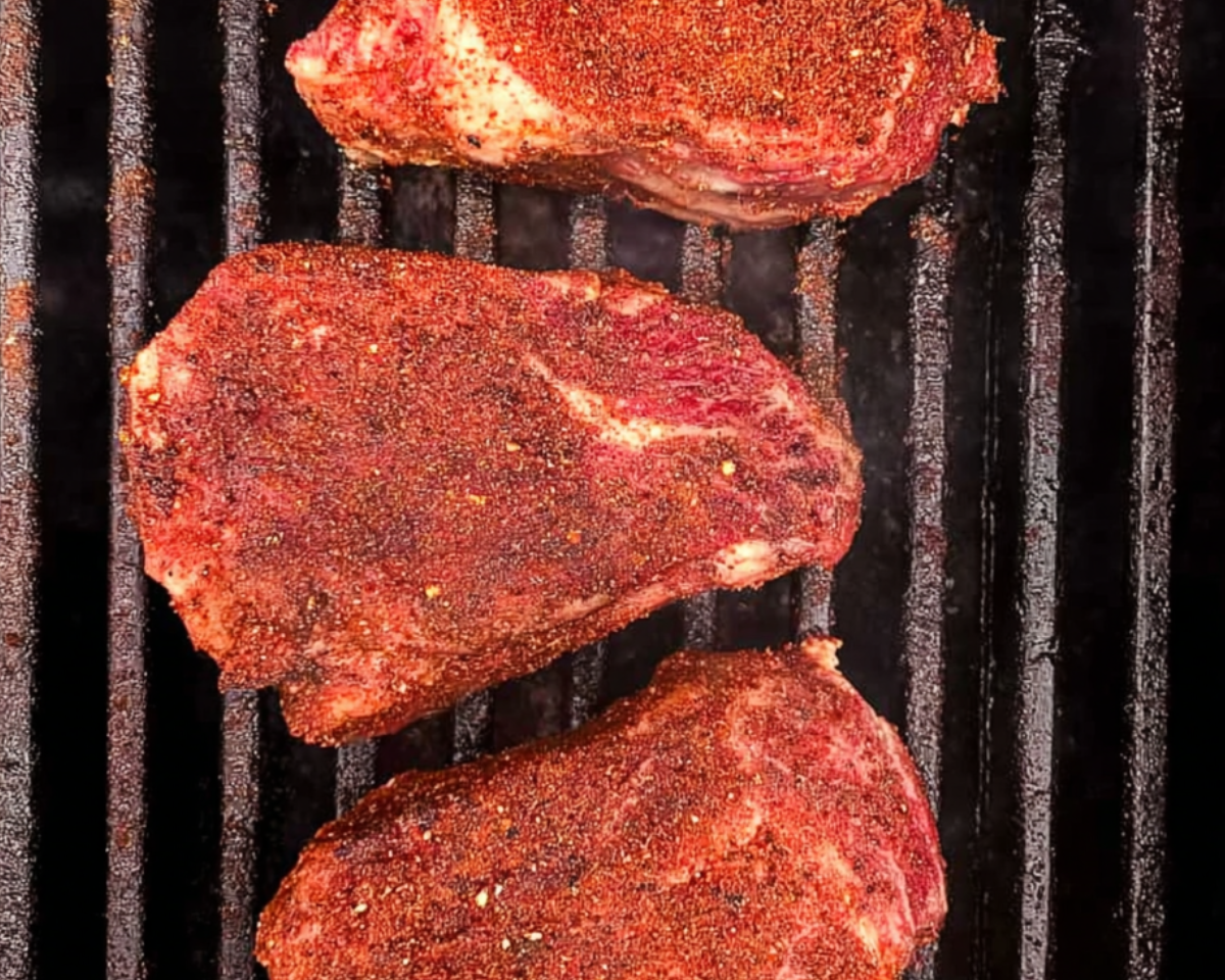 seasoned steaks on grill